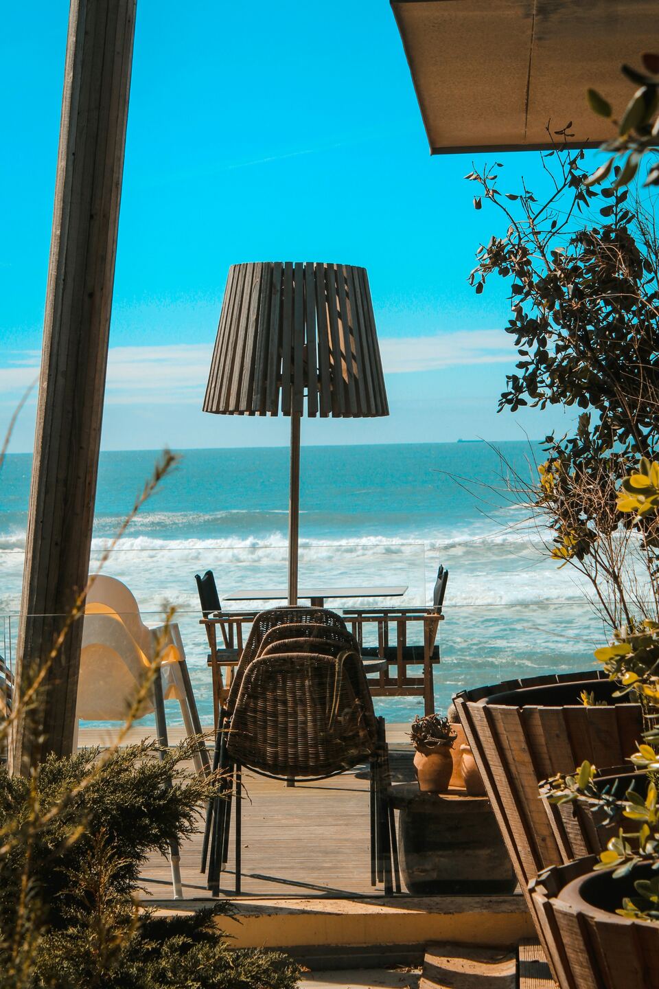 Esplanada com mesas e candeeiro de palha virada para o mar